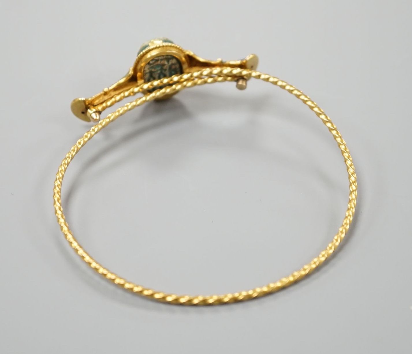 A late 19th/early 20th century yellow metal, polychrome enamel and scarab set hinged bangle, interior diameter 58mm, gross weight 11.7 grams.